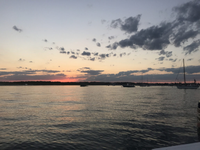 Beautiful sunset over Barnstable Harbor with pink at shoreline and fluffy clouds