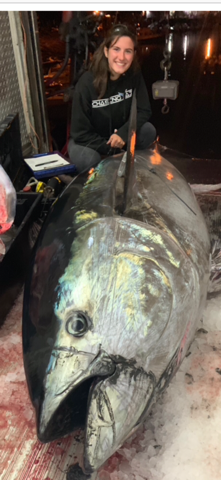 Young woman with enormous bluefin tuna on boat deck