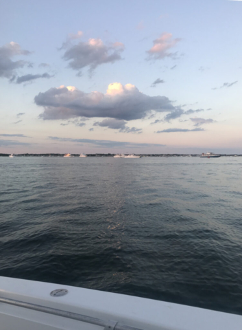 Sunrise on the ocean with blue sky, fluffy clouds and pink tinge