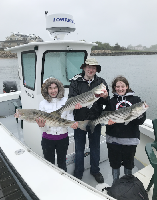 Three teens smiling on the Ali J with their striped bass